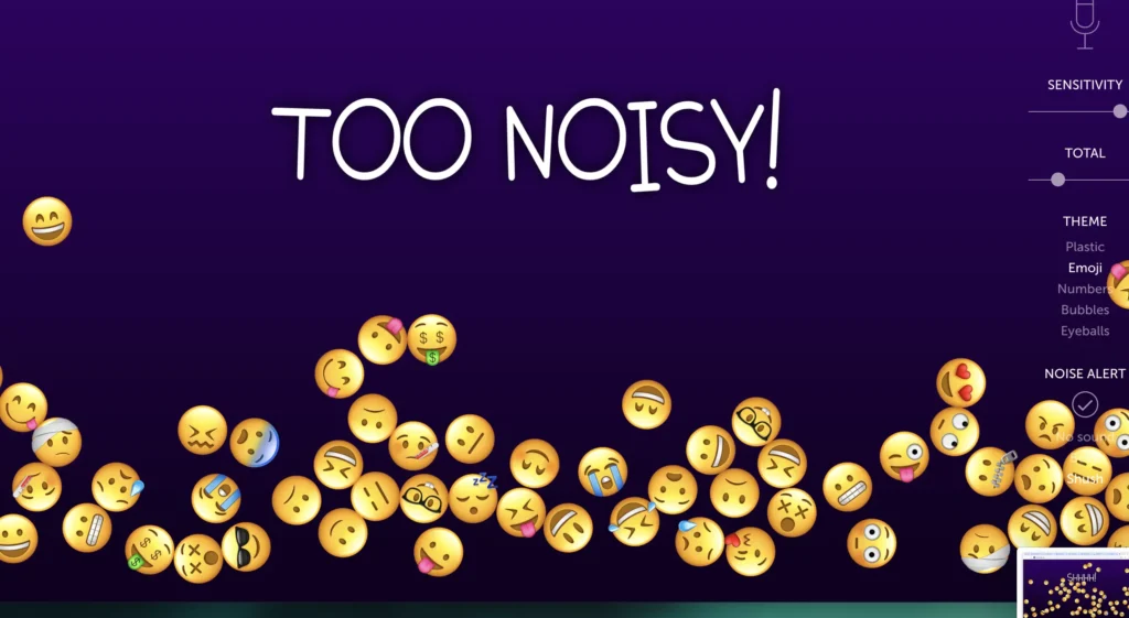 A classroom noise monitoring screen from BouncingBalls.org. A variety of emoji faces expressing different emotions are scattered across the bottom of the screen. The large text in the middle reads ‘TOO NOISY!’ against a dark purple background. A control panel on the right side shows options for sensitivity, total noise, and themes