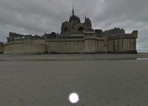 Screenshot from Google Arts & Culture’s Talking Tours, showing Mont Saint-Michel, the historic island commune in Normandy, France, with its distinct medieval architecture and surrounding sandy tidal area.