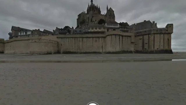 Screenshot from Google Arts & Culture’s Talking Tours, showing Mont Saint-Michel, the historic island commune in Normandy, France, with its distinct medieval architecture and surrounding sandy tidal area.